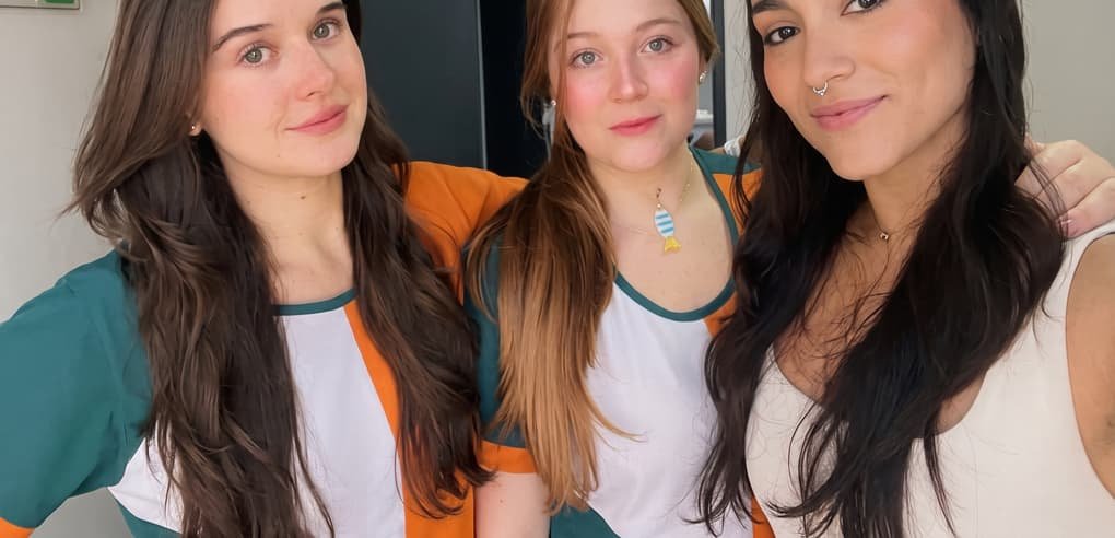 Katherynne, a la izquierda, junto a dos compañeras del equipo, con uniformes verdes y naranja